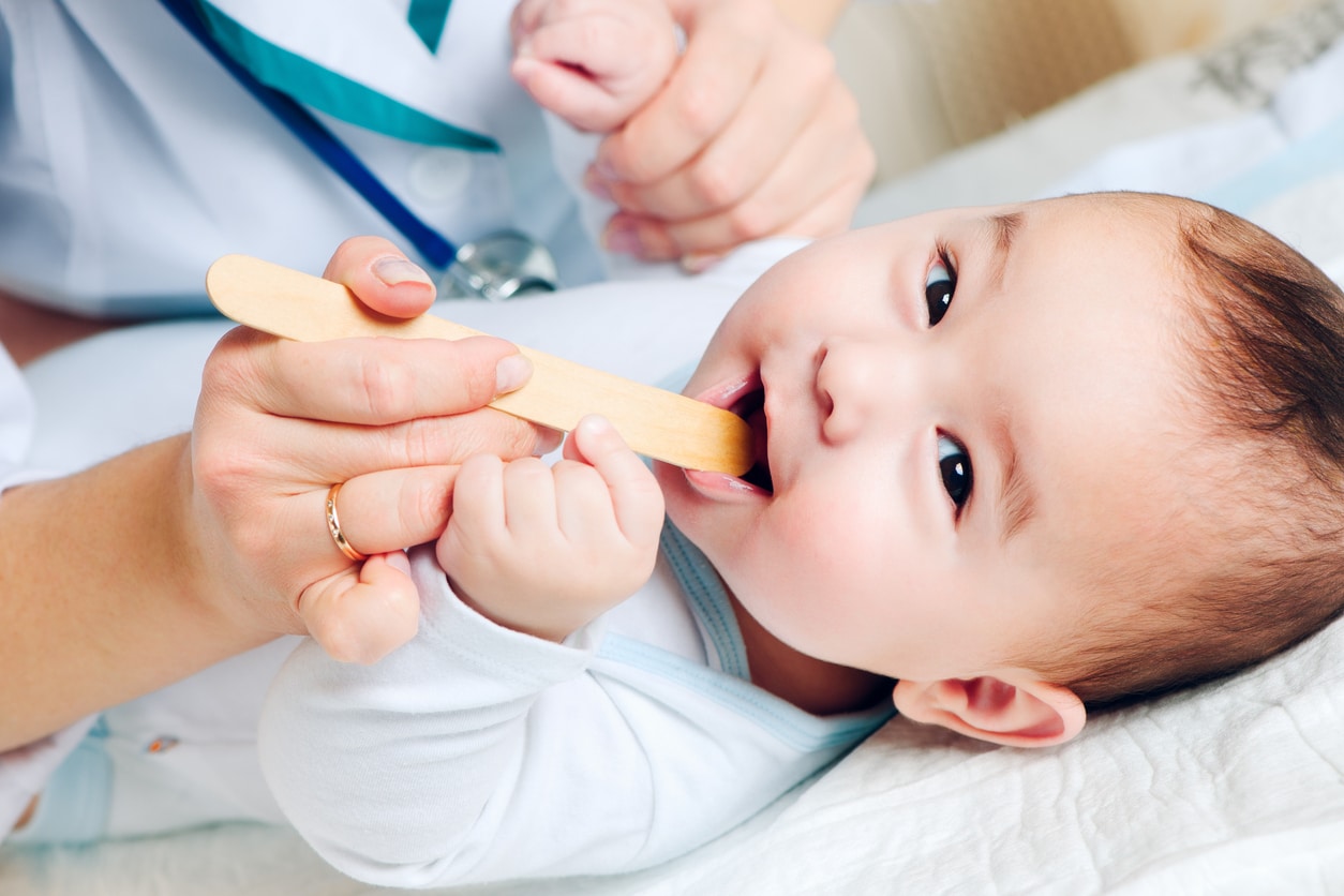 Pediatrician examines a cute baby's throat
