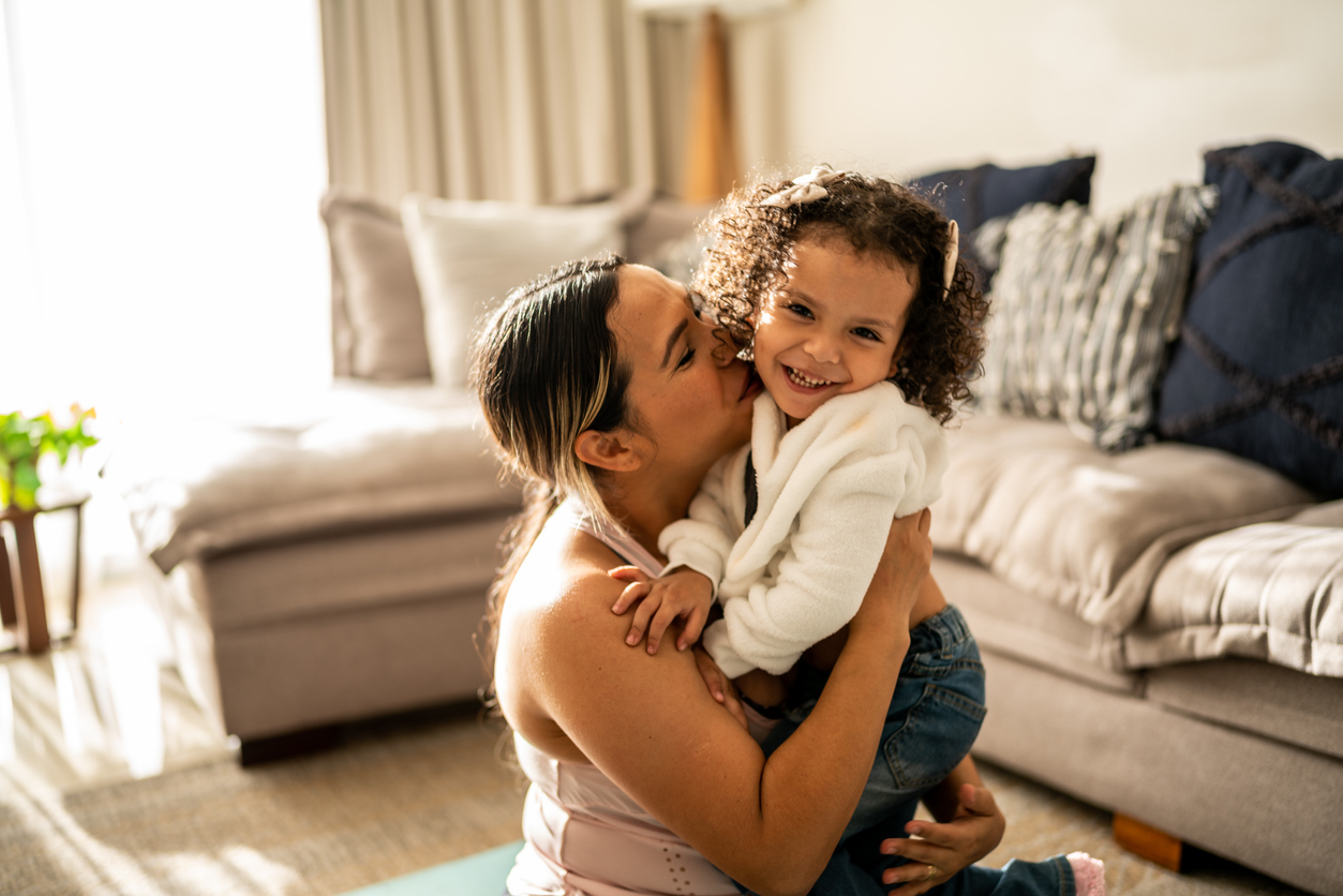 Portrait of a little girl having fun with her mother in the living room at home