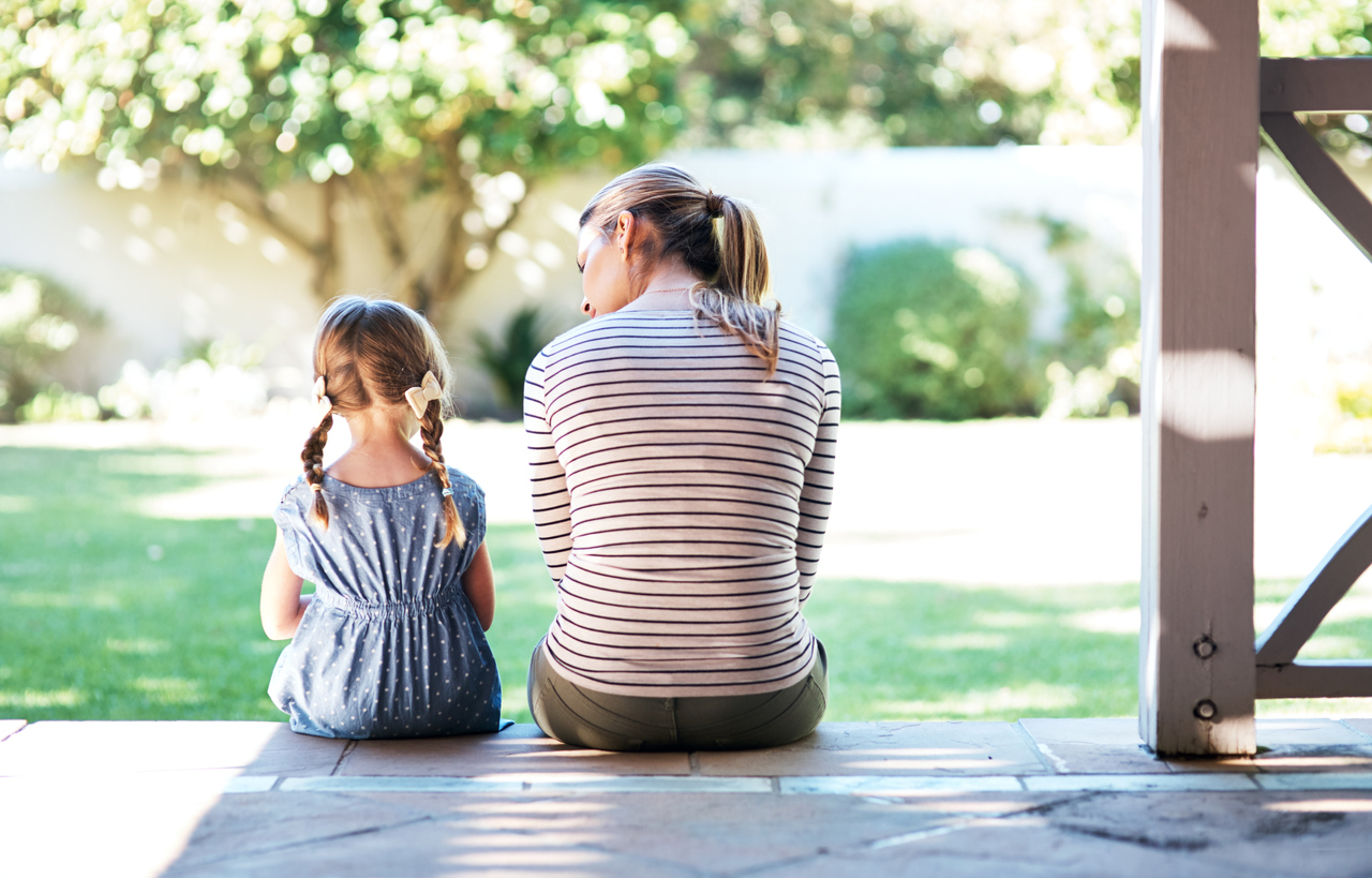 Life doesn't come with a manual but with mom. Rear view of a young woman and her daughter talking on the porch.