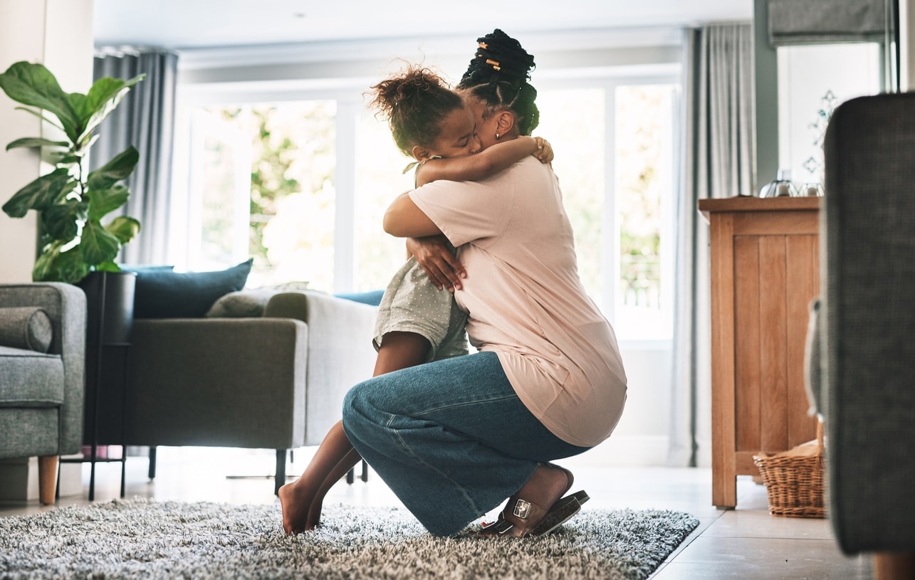 Shot of a mother and child hugging in the living room at home.