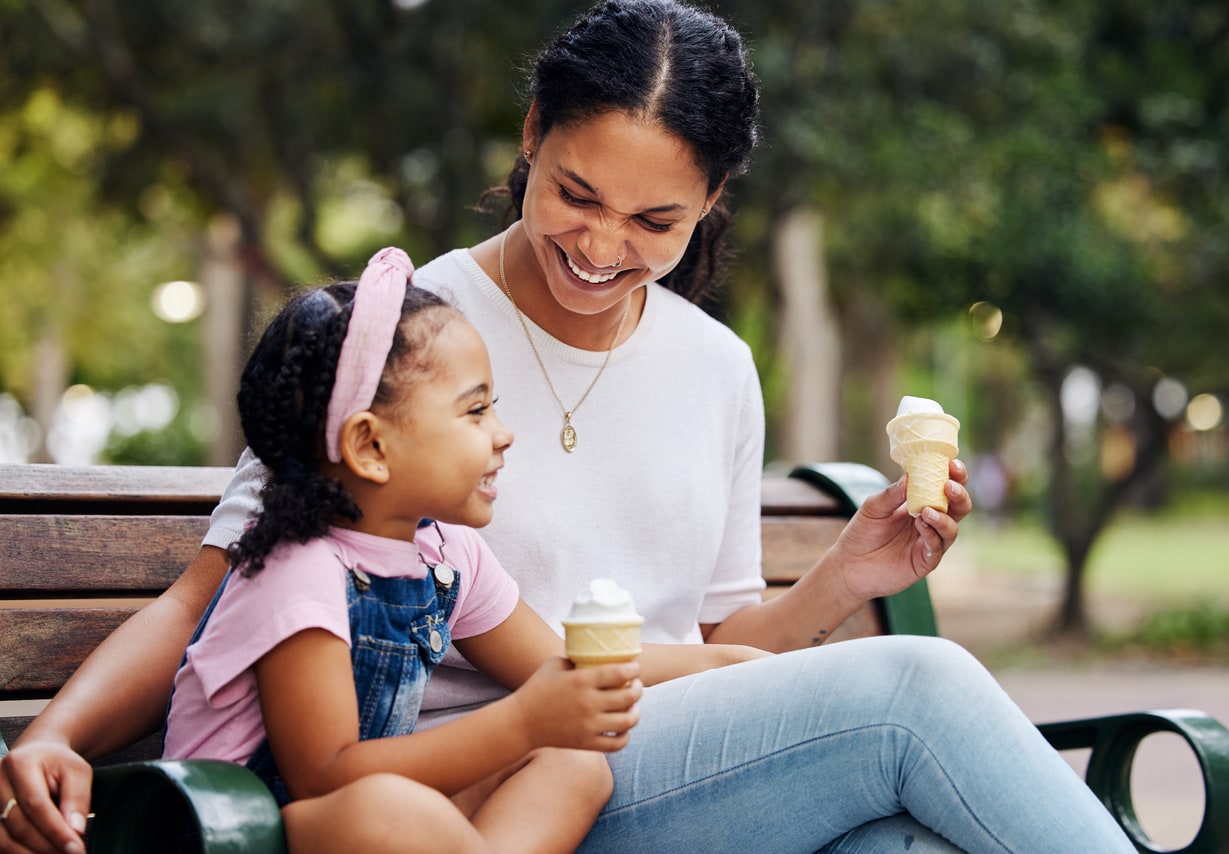 Summer, park and ice cream with a mother and daughter bonding while sitting on a bench outside in nature. Black family, children and garden with a woman and a girl enjoying a sweet snack