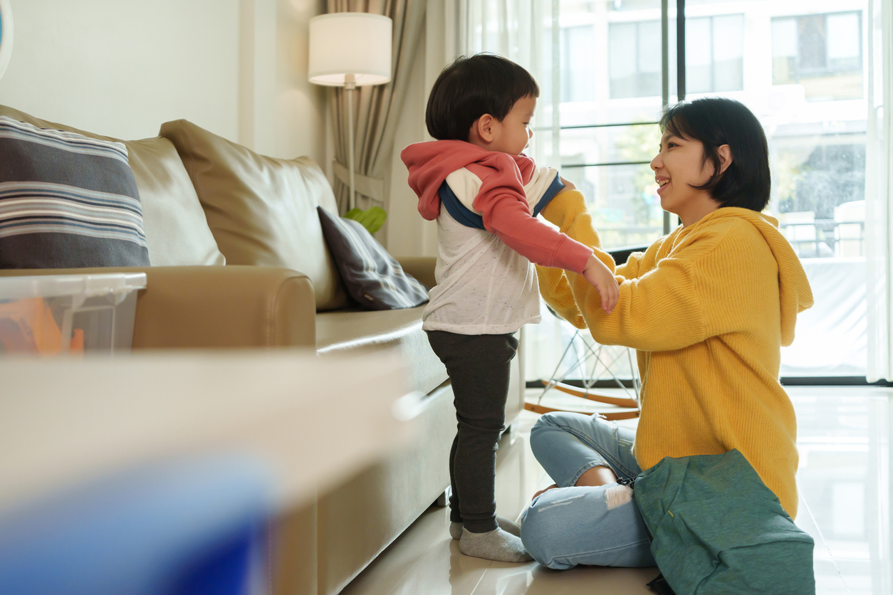 Happy Asian Chinese mother dressing her son in a winter coat for the first day of school. We are preparing to return to school.