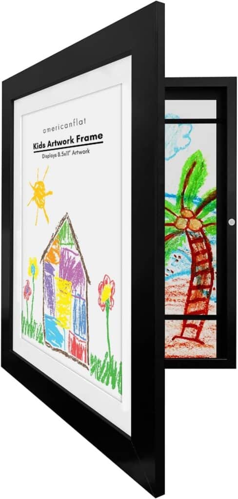 A black picture frame with a white mat that features a colorful child's drawing of a house, sun, and flowers. The frame opened reveals another drawing of a palm tree and beach inside. The text on the frame reads
